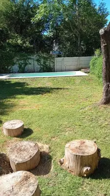 two logs sitting in the grass next to a tree at Cabaña - casa - chalet con pileta a minutos de Villa Carlos Paz para 8 personas in San Roque
