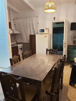 a kitchen with a large table with chairs and a refrigerator at Cabaña - casa - chalet con pileta a minutos de Villa Carlos Paz para 8 personas in San Roque