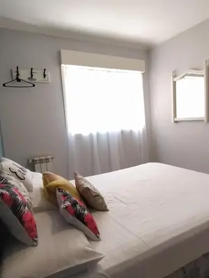 a bedroom with a white bed with pillows and a window at Departamento de los Cuadros in Villa Carlos Paz