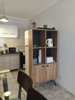 a kitchen with a wooden book shelf with a microwave at Departamento de los Cuadros in Villa Carlos Paz