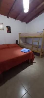 a bedroom with a red bed and a wooden bunk bed at Brisas de Montaña in Mina Clavero