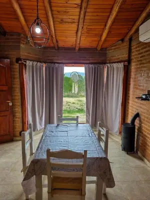 a dining room table with chairs and a large window at Brisas de Montaña in Mina Clavero