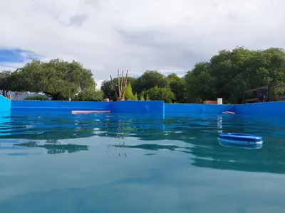 a pool of blue water with a blue fence at Brisas de Montaña in Mina Clavero