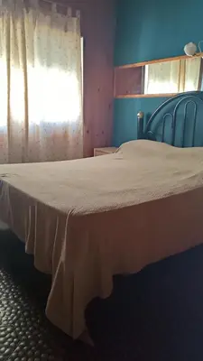 a bedroom with a bed with a white bedspread and a window at Depto en planta alta in Villa Carlos Paz