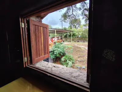an open window with a view of a garden at Stone Cabin, PETRA HAUS in Cuesta Blanca