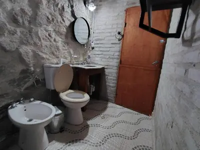a bathroom with a toilet and a sink and a mirror at Stone Cabin, PETRA HAUS in Cuesta Blanca