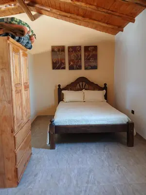 a bedroom with a bed and a wooden cabinet at La soñada in San Antonio de Arredondo