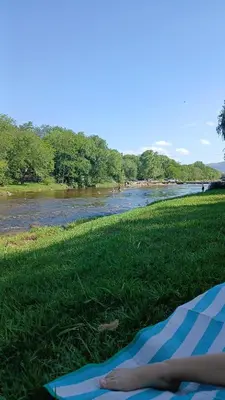 a person laying on a blanket on the grass next to a river at La soñada in San Antonio de Arredondo