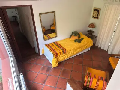 a bedroom with a bed with a yellow blanket and a mirror at CASA DE CAMPO con bajada al rio in Villa Los Aromos