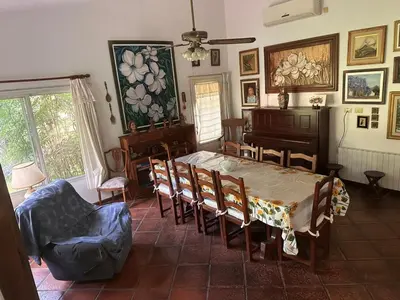 a dining room with a table and chairs and a piano at CASA DE CAMPO con bajada al rio in Villa Los Aromos