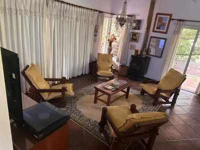 a living room with yellow chairs and a tv at CASA DE CAMPO con bajada al rio in Villa Los Aromos