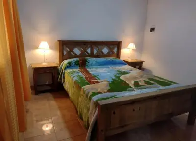 a bed in a bedroom with two lamps on two tables at Cabañas Los Dos Talas in Barrio Parque El Corcovado