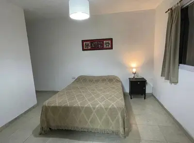 a bedroom with a bed and a table with a lamp at PEPINA Villa Cura Brochero in Villa Cura Brochero