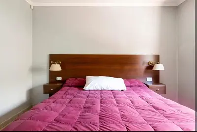 a large bed with a pink comforter in a bedroom at Casa D'amico in Villa General Belgrano
