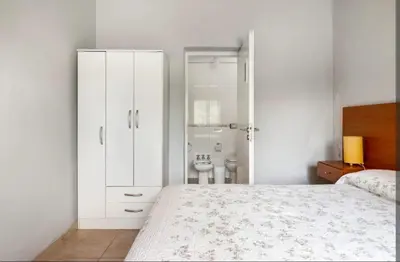 a white bedroom with a bed and a bathroom at Casa D'amico in Villa General Belgrano