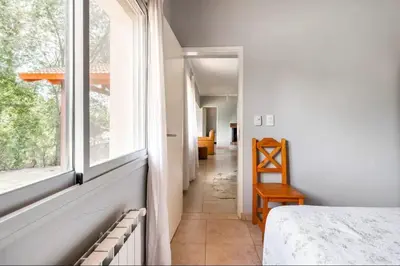 a room with a bed and a window and a hallway at Casa D'amico in Villa General Belgrano