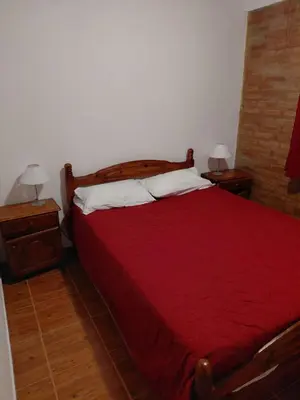 a bedroom with a red bed with two night stands at familia olivares in Villa Carlos Paz