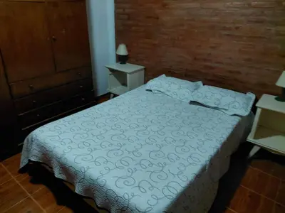 a bedroom with a bed with a white comforter at familia olivares in Villa Carlos Paz