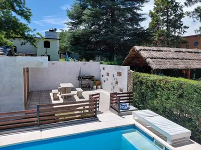 a backyard with a pool and benches and a house at familia olivares in Villa Carlos Paz