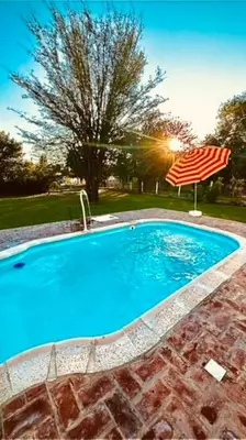 a large blue swimming pool with an umbrella at Mirador Rest House - Casa entera con pileta privada in Bialet Massé
