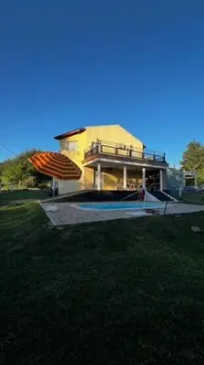 a house with an umbrella in front of it at Mirador Rest House - Casa entera con pileta privada in Bialet Massé