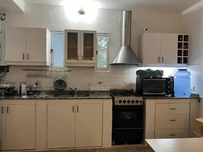 a kitchen with white cabinets and a black stove top oven at Mirador Rest House - Casa entera con pileta privada in Bialet Massé