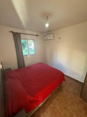 a red bed in a room with a window at Cabañas con pileta y aire acondicionado empalme in Villa Carlos Paz