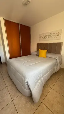 a bedroom with a large bed with a yellow pillow at Güemes Apartamento in Cordoba