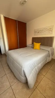 a large bed with a yellow pillow on top of it at Güemes Apartamento in Cordoba