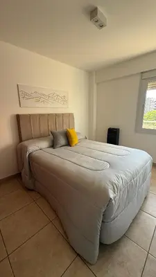 a bedroom with a large bed with a yellow pillow at Güemes Apartamento in Cordoba