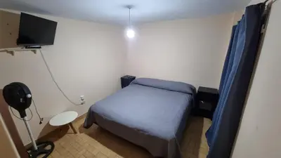a small bedroom with a blue bed and a television at centro apartment in Cordoba
