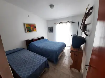 a bedroom with two beds and a television in it at Marisa departamento temporario in Villa Carlos Paz