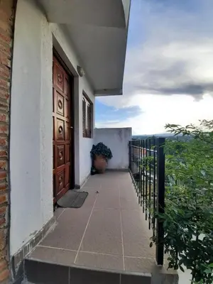 a door to a building with a balcony with a plant at Marisa depto temporario in Villa Carlos Paz