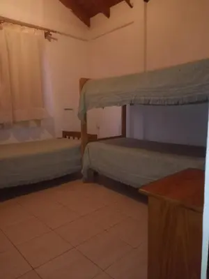 a room with two beds and a table in a room at Posada Del Galés in Los Molles