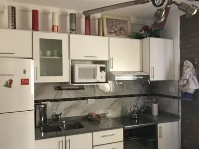 a kitchen with white cabinets and a sink and a microwave at Dúplex Carlos Paz in Villa Carlos Paz