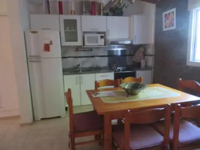 a kitchen with a wooden table with chairs and a refrigerator at Dúplex Carlos Paz in Villa Carlos Paz