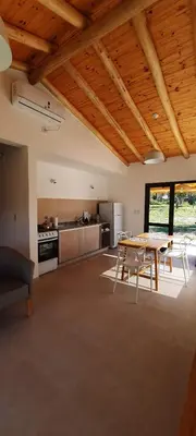 a living room with a table and a kitchen at Casa de Campo Roca - Exclusivo para Parejas in Villa Cura Brochero