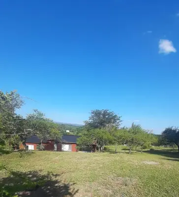 a house on a hill with a field and trees at Cabañas Piscu Yaco in Santa Rosa de Calamuchita