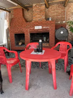 a red table and two chairs and a brick fireplace at La soñada AG in Alta Gracia