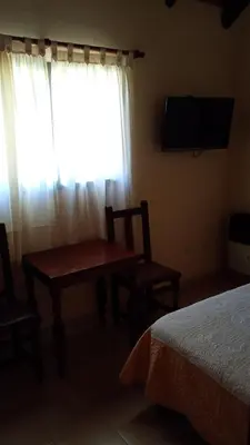 a bedroom with a table and a window with a television at Hostería Sueños Dorados in Merlo