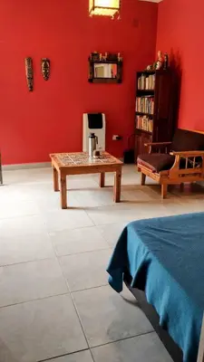 a living room with a table and a red wall at Casa de Ceci in Villa Carlos Paz