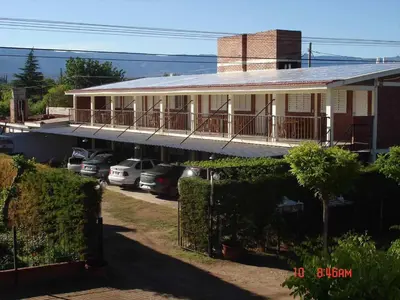 a house with cars parked in front of it at El Pino Departamentos in Villa Cura Brochero