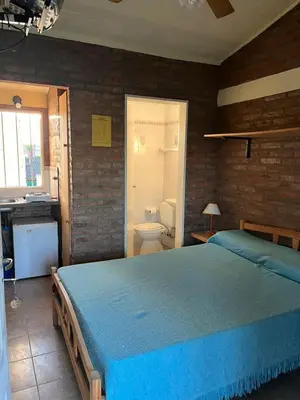 a bedroom with a blue bed and a bathroom at El Pino Departamentos in Villa Cura Brochero