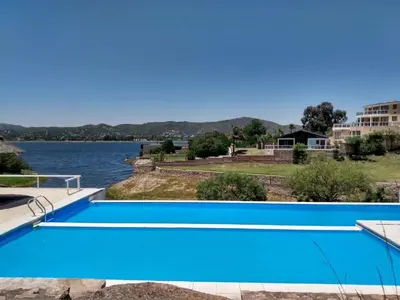 a large blue swimming pool next to a body of water at Casa Mabel in La Porteña