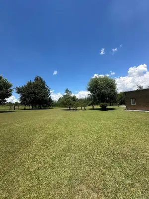 a large field of grass with trees and a building at Mi lugar Potrero de Garay in La Estancia