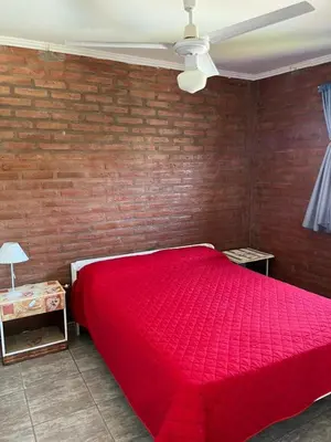 a red bed in a bedroom with a brick wall at Complejo cerca del rio in Villa Carlos Paz