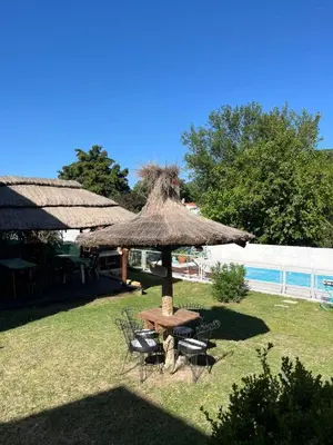 a picnic table and chairs under a straw umbrella at Complejo cerca del rio in Villa Carlos Paz