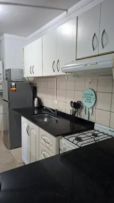 a kitchen with white cabinets and a sink and a stove at Departamento 2 H VIRREY in Villa Carlos Paz
