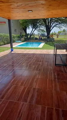 a wooden floor with a bench and a swimming pool at Casa de campo Los Gurises in Alta Gracia