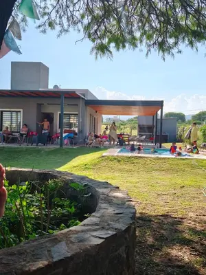 a house with a pool and people in a yard at Casa de campo Los Gurises in Alta Gracia